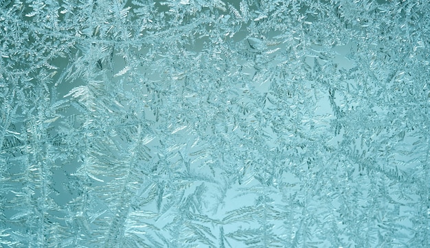 Foto patrón escarchado en el cristal de la ventana. pared azul de invierno