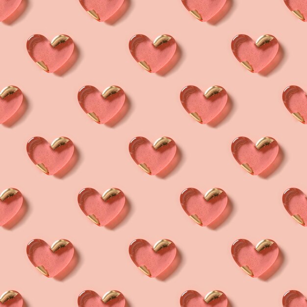 Patrón sin fisuras del día de san valentín de dulces rosas en forma de corazón sobre fondo rosa