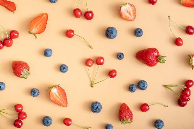 Patrón con fresas, cerezas y frambuesas sobre un fondo naranja