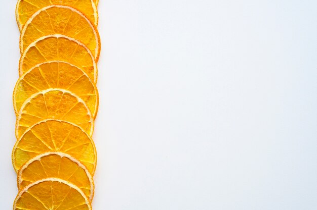 Foto patrón de fruta de una fila de rodajas de naranja secas dispuestas en el lado sobre un fondo blanco. espacio para texto