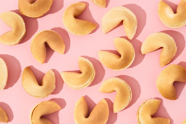 Patrón con galletas de la fortuna sobre fondo rosa con sombras largas y profundas