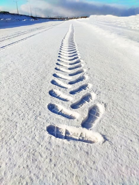 Patrón de huella de zapato en la nieve que se extiende en la distancia