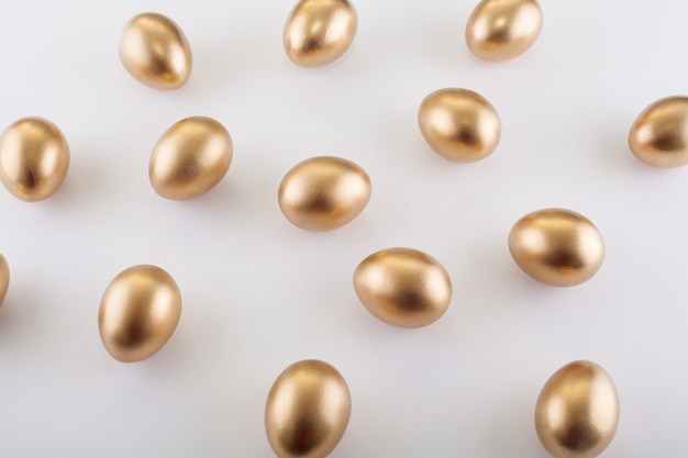 Patrón de huevos de oro sobre una mesa blanca