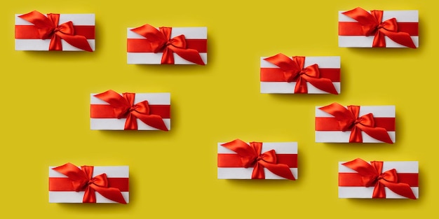 Patrón minimalista con cajas de regalo con cinta roja.
