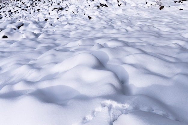 Patrón de onda cubierto de nieve blanca esponjosa en la colina en invierno