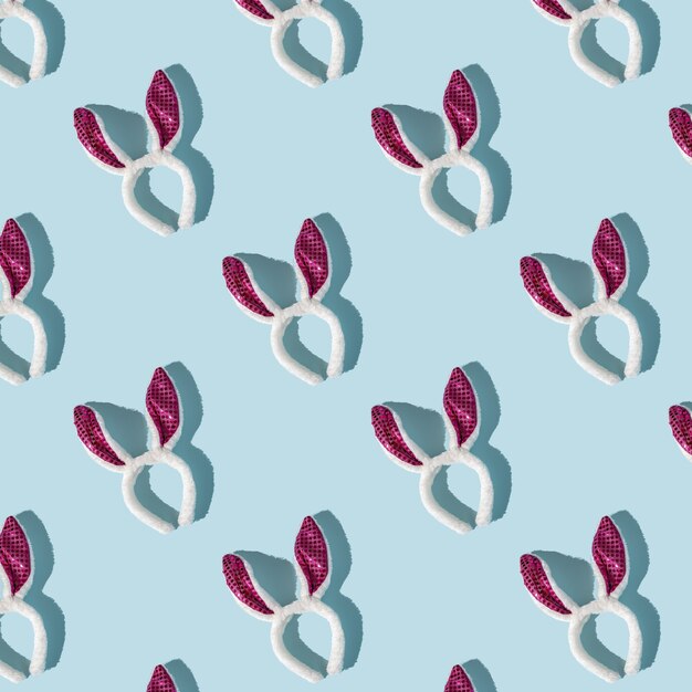 Patrón de Pascua de orejas de conejo rosa y blanco sobre fondo azul, vista superior, sombras fuertes