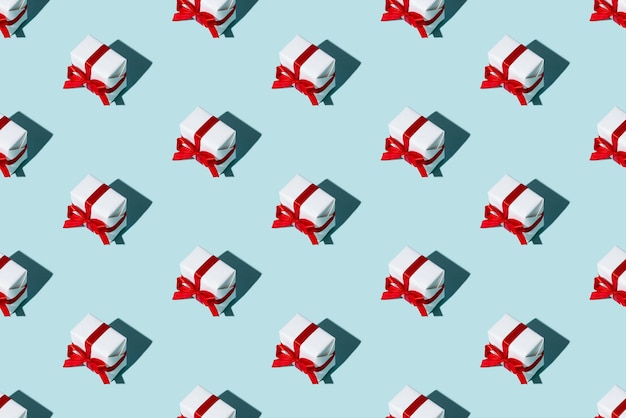 Foto patrón de regalo. fondo transparente azul. venta de vacaciones. composición festiva. arreglo simétrico minimalista de cajas blancas con lazos de cinta roja aislados en la luz.