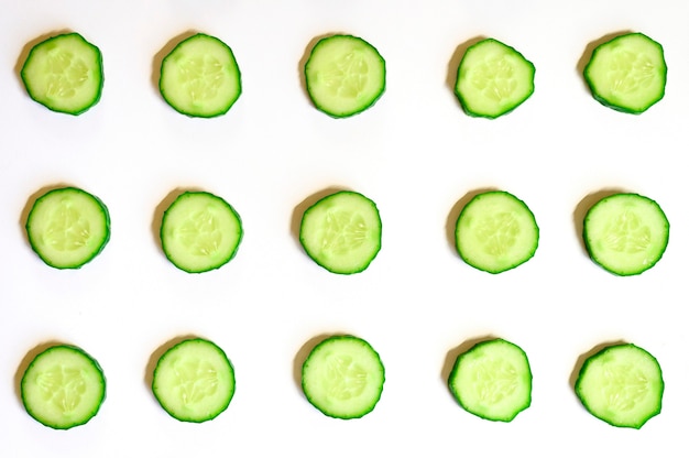 Foto patrón repetitivo de semicírculos en rodajas de pepinos vegetales crudos frescos para ensalada aislado en un fondo blanco endecha plana, vista superior