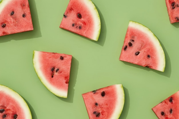 Patrón de sandía de papel tapiz creativo de verano con fruta en rodajas de luz solar sobre fondo verde