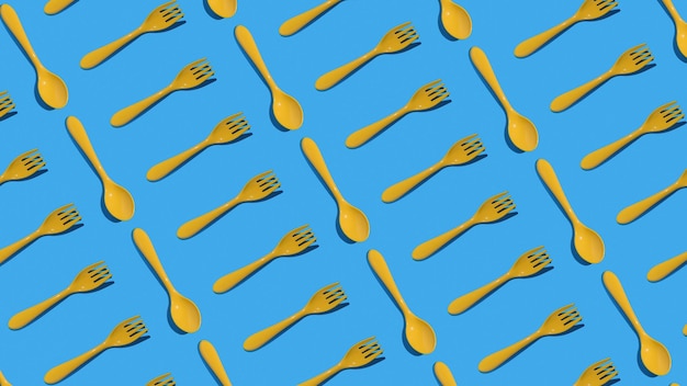 Un patrón de tenedores y cucharas de plástico amarillo sobre un fondo azul Concepto mínimo de accesorios de cocina