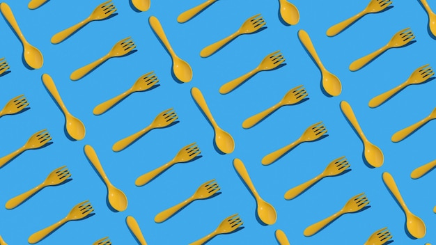 Un patrón de tenedores y cucharas de plástico amarillo sobre un fondo azul Concepto mínimo de accesorios de cocina