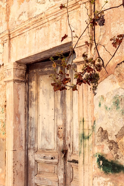 El patrón de textura El fondo de la vieja pared beige con yeso pelado y puerta retro