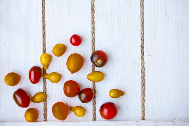 Patrón de tomates orgánicos frescos amarillos y rojos sobre un fondo blanco con cuerda. enfoque suave