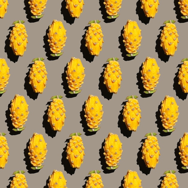 Patrón tropical de mitades de pitahaya amarilla sobre un fondo gris