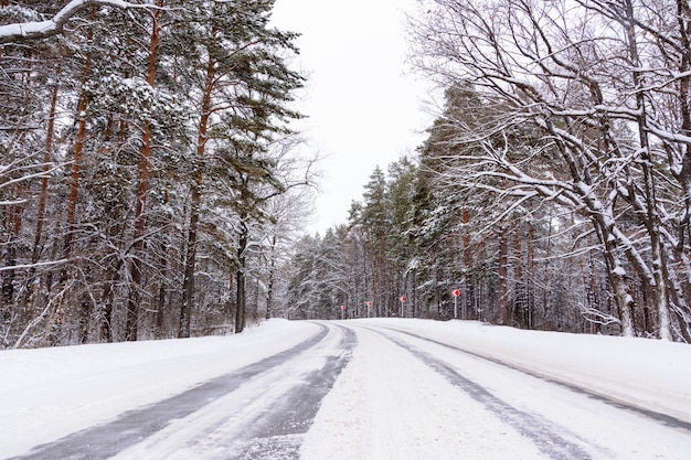 Patrones en la carretera de invierno en forma de cuatro líneas rectas. Camino nevado en el fondo del bosque nevado. Paisaje de invierno.