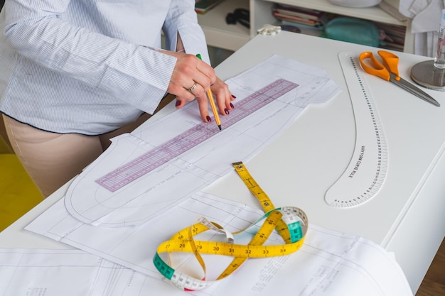 Patrones de papel de dibujo de diseñador femenino Concepto exclusivo de fabricación de ropa Lugar de trabajo de costurera