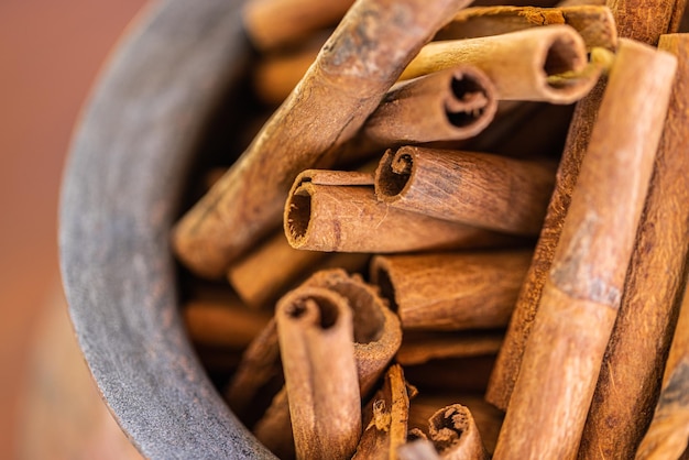 Foto paus de canela aromáticos em tigela na mesa de madeira marrom, closeup. papel de parede artístico de ingredientes alimentares