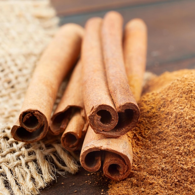 Paus de canela e pó em colher de madeira