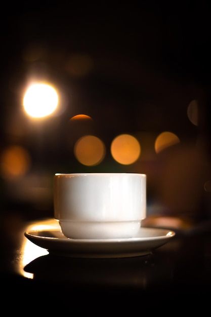 Pausa para el café Ceremonia del té Taza de porcelana y tetera contra el fondo de guirnaldas de luces