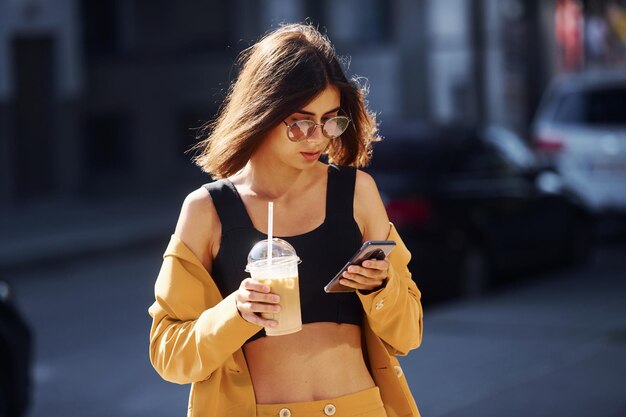 Pausa para el café Joven mujer de moda con abrigo de color burdeos durante el día con su coche