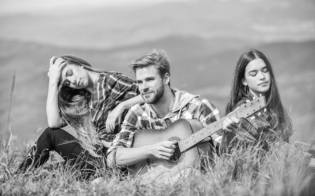 Pausa musical Caminhada entretenimento Lugar tranquilo Melodia da natureza Tradição de caminhada Amigos caminhando com música Pessoas relaxando no topo da montanha enquanto homem bonito tocando violão Cantando juntos