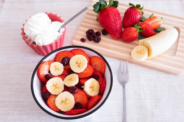 Pausa saudável e doce ou café da manhã com uma xícara de morango, amora vermelha e banana Um pouco de creme para os gananciosos