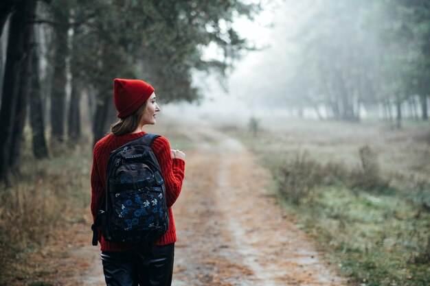 Pausas de fim de semana e fugas nas florestas ficam perto da natureza jovem de chapéu vermelho e suéter com