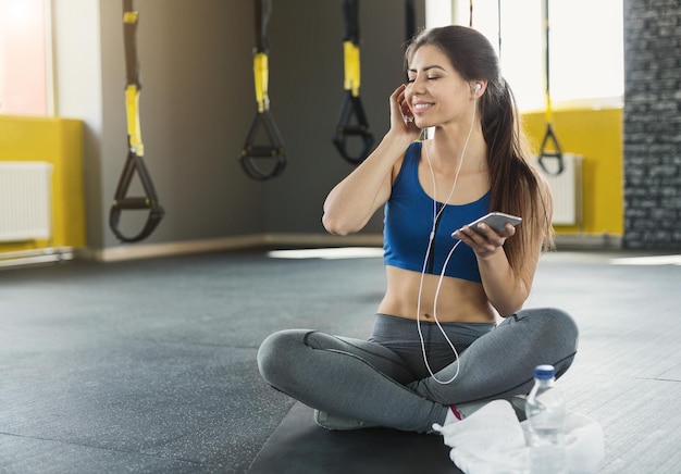 Pause nach dem Training. Sportliche Frau, die Musik auf dem Smartphone im Fitnessstudio genießt, Platz kopieren