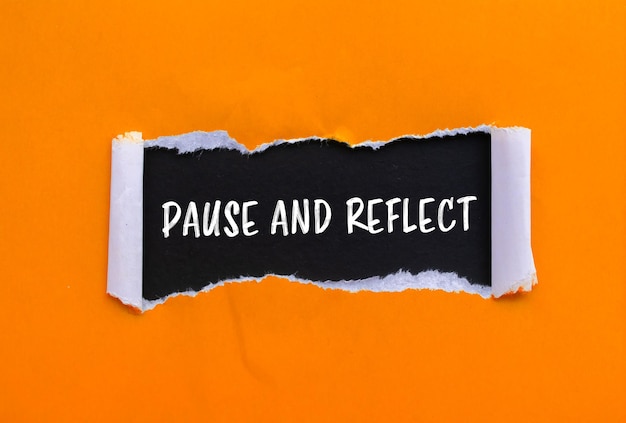 Pause und Reflect-Nachricht geschrieben auf zerrissenem orangefarbenem Papier mit schwarzem Hintergrund Konzeptuelles Pause- und Reflex-Symbol Kopieren Sie den Raum