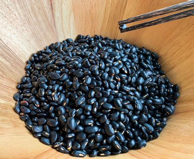 Foto pauzinhos em cubos de feijão preto em uma tigela de madeira, propriedades ajudam a desintoxicar e nutrir os rins também. devido à presença de flavonóides e antocianinas, ricos em proteínas, impedindo a anemia devido a i