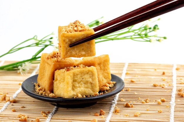 Pauzinhos estão martelando tofu frito 1 peça Tofu frito é empilhado polvilhado com amendoim.