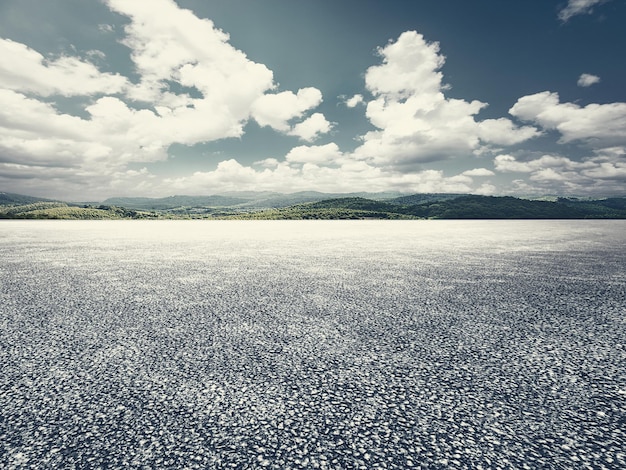 Pavimento de asfalto vacío y montañas sin coches y nadie bajo el cielo azul