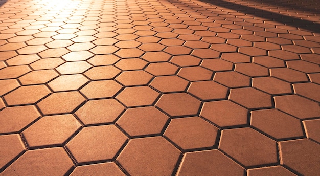 Pavimento de paralelepípedos marrom hexagonal em estilo vintage com luz solar dourada e sombra na superfície