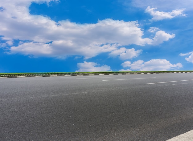 Pavimentos de asfalto y baldosas cuadradas bajo el cielo azul y nubes blancas