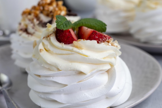 Pavlova-Baiser-Kuchen mit Schlagsahne und frischen Erdbeerminzblättern Selektiver Fokus