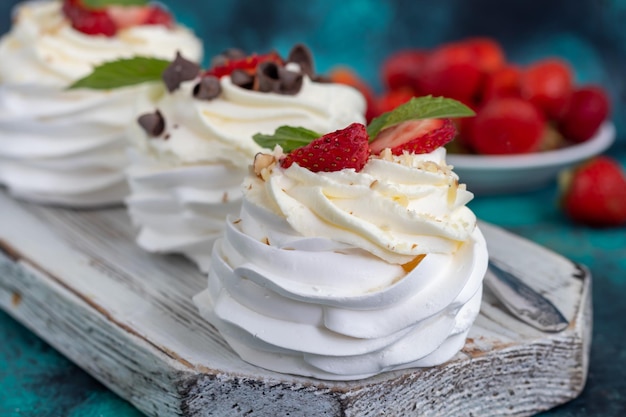 Foto pavlova-baiser-kuchen mit schlagsahne und frischen erdbeerminzblättern selektiver fokus