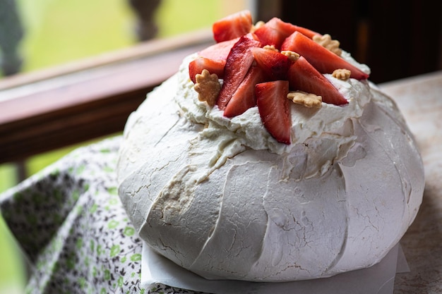 Pavlova-Sommer-Nachtisch mit frischen Früchten in der Nähe des Fensters