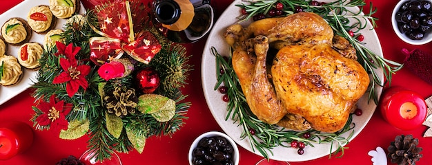 Pavo al horno Cena de Navidad. La mesa navideña se sirve con un pavo, decorado con brillantes guirnaldas y velas. Pollo frito, mesa. Cena familiar. Vista superior