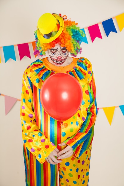 Foto payaso aterrador y bola roja. violencia y miedo infantil