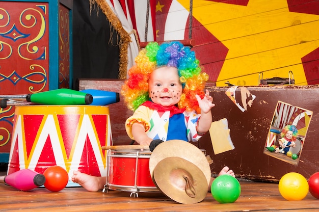 Foto payaso bebé con peluca multicolor nariz roja con bolas.