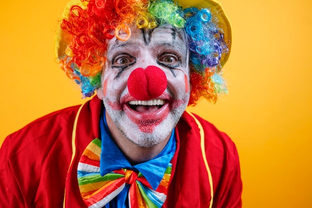 Un payaso feliz con un traje colorido contra un fondo amarillo vibrante