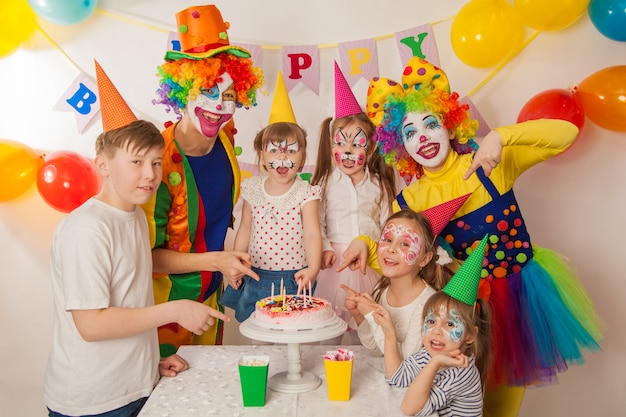 payaso niña y niño payaso en la fiesta de cumpleaños de los niños. Mesa festiva con un hermoso pastel