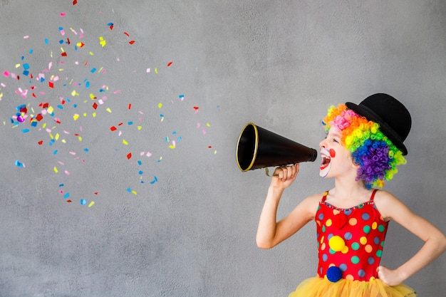 Payaso niño divertido. Niño hablando con megáfono. Concepto del día de los inocentes del 1 de abril