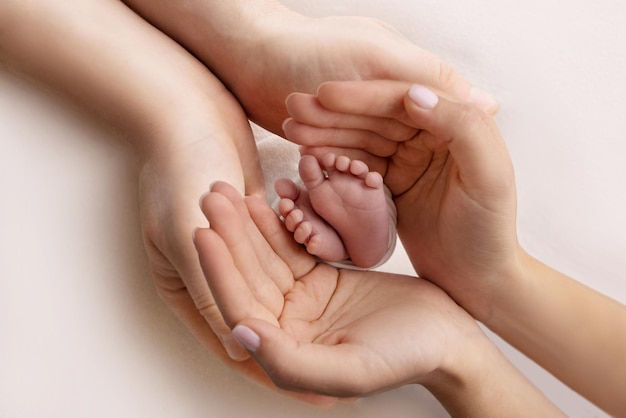 Pé de criança nas mãos da mãe pai pais Pés de um recém-nascido minúsculo perto Pernas de bebê mãe e seu filho Conceito de família feliz Linda imagem conceitual da maternidade foto de stock