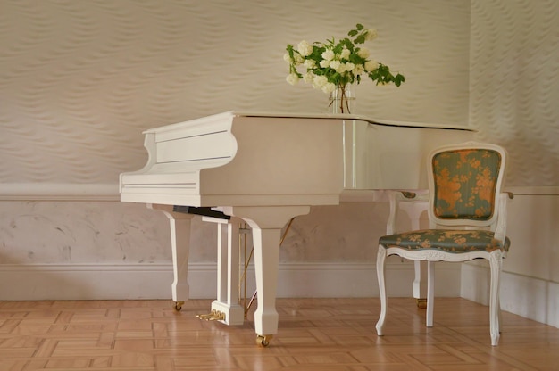 Pé de piano de cauda branco no elegante interior branco do salão do palácio. piano branco na sala de reto vazia com cadeira