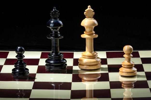 Peça de xadrez de peão preto e rei em pé face marrom rei e peça de xadrez  de peão no tabuleiro de xadrez