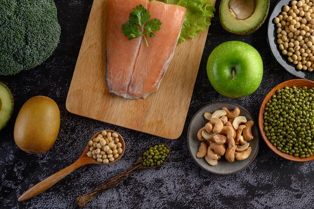 Foto peças de leguminosas, frutas e peixes de salmão numa tábua de cortar de madeira