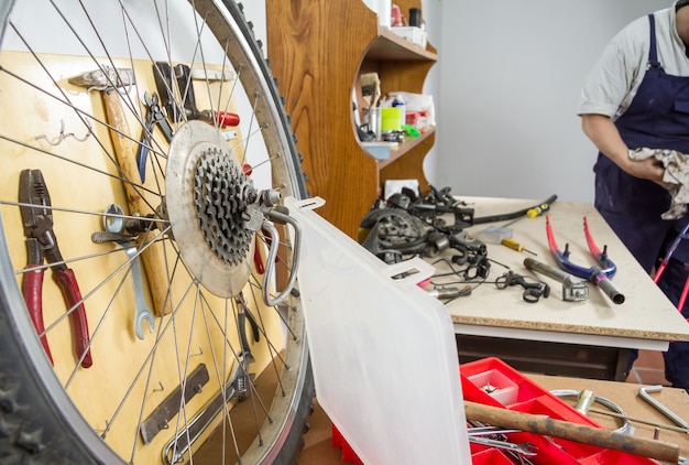 Peças de roda e bicicleta sobre mesa de oficina no processo de restauração de uma bicicleta danificada