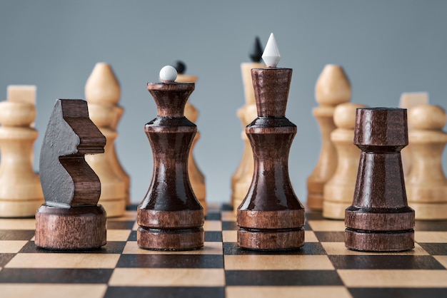 Peças de xadrez de madeira em um tabuleiro de xadrez, peças pretas em uma fileira, peças brancas no fundo, conceito, estratégia, planejamento e tomada de decisão