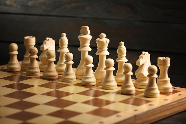 Peças de xadrez e tabuleiro de jogo em fundo de madeira